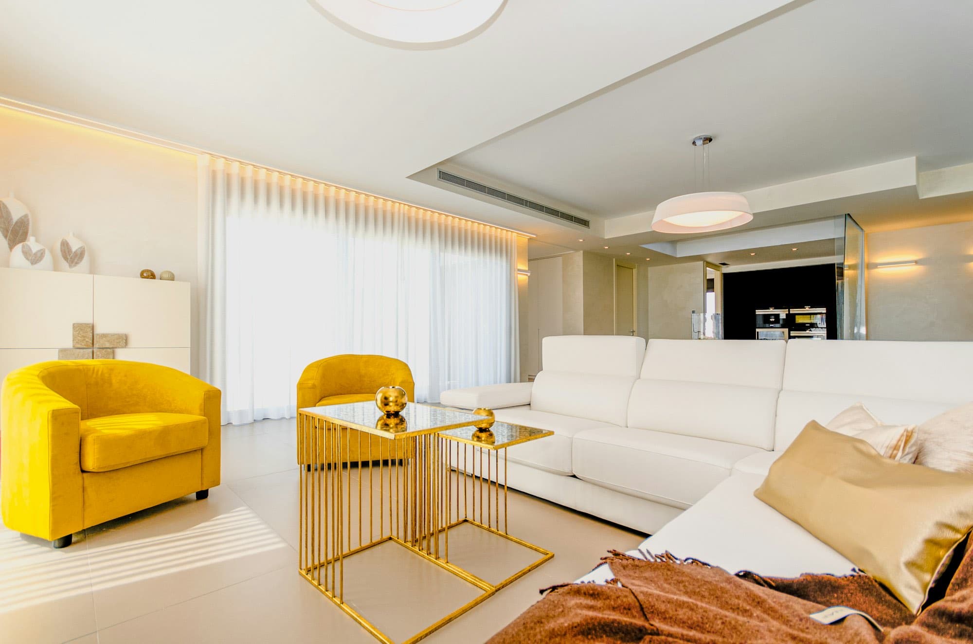A pale interior with two yellow armchairs and a marble table